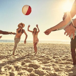 playful-young-friends-playing-with-beach-ball-on-sunny-summer-beach-CAIF04822